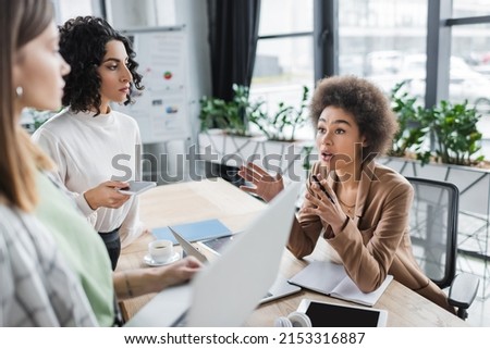 African american businesswoman talking to multiethnic colleagues with gadgets in office