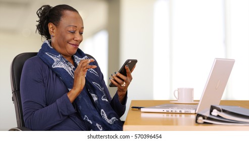 An African American businesswoman uses her mobile phone at her desk