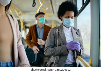 African American Businesswoman Wearing Face Mask And Protective Gloves While Text Messaging On Mobile Phone And Commuting To Work By Bus. 