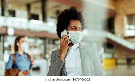 African American Businesswoman Wearing Protective Mask While Communicating On Mobile Phone At The Airport. 