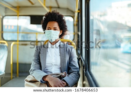 African American businesswoman wearing protective mask while traveling by public transportation. 