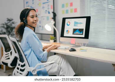 African american businesswoman is working late in the office, focused on her computer screen and wearing a headset for a conference call - Powered by Shutterstock