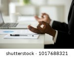 African american calm businessman relaxing meditating in office, peaceful ceo in suit practicing yoga at work, focus on black man hands in mudra, successful mindful people habits concept, close up