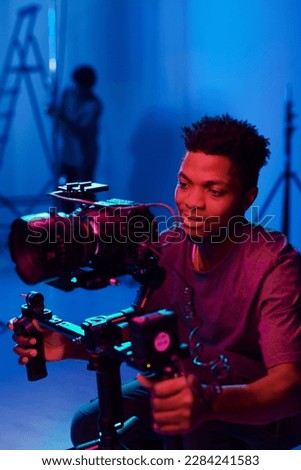 African American camera operator using professional camera to shoot process in studio