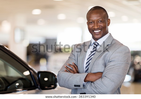 african american car dealership principal\
standing in vehicle\
showroom