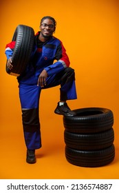African american car service worker with car tyre against yellow background - Shutterstock ID 2136574887