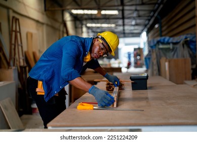 African American carpenter man use tape measure to work with timber on table during work in factory workplace area. - Shutterstock ID 2251224209