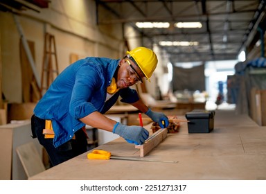 African American carpenter man use pencil to mark on timber during work with in wood factory workplace.