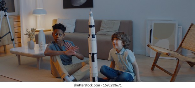 Amigos afroamericanos y caucásicos trabajando en un modelo de cohete para un proyecto de luna-aterrizaje. Inteligente, ciencia, niños soñadores