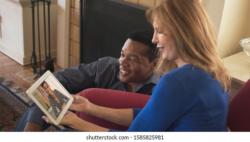 African American And Caucasian Couple Video Chatting With Daughter On Tablet Computer. Older Couple Facetiming On Tablet Computer With Daughter