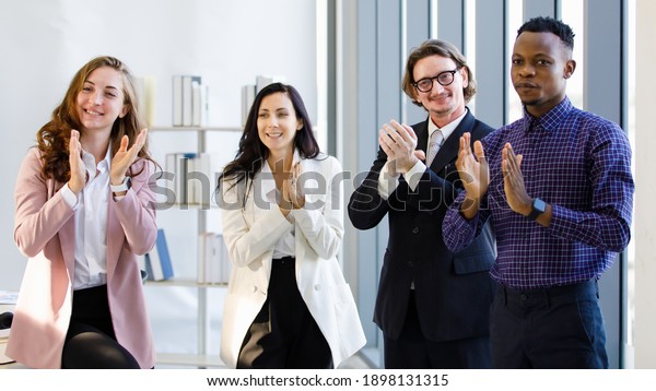 African American and caucasian four people\
business Conference on office building structure design and\
success, Everyone stood up and clapped their hands. Concept group\
meeting in office