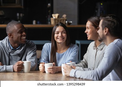 African American and Caucasian friends chatting in cozy cafe, drinking coffee, smiling diverse people having fun in coffeehouse together, enjoying pleasant conversation at coffee break - Powered by Shutterstock