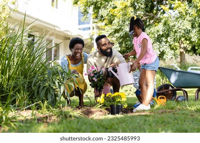 African american cheerful parents with children planting and watering flowers on field in backyard. Unaltered, lifestyle, gardening, family, love, togetherness, nature, weekend and childhood concept. - Powered by Shutterstock