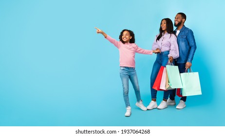 African American cheerful people holding shopping bags pointing aside