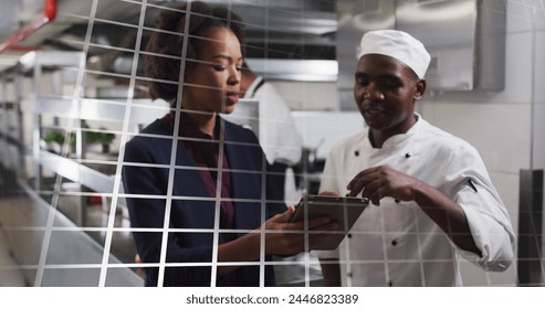 African American chef and young African American woman review a tablet in a busy kitchen. They are collaborating in a professional culinary setting, discussing recipes or orders. - Powered by Shutterstock