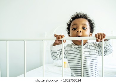 African American child boy stand near bed rail play and he look happy and innocent. Concept of happiness emotion occur with good health and support from family.