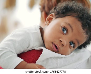 African American child is sleeping on the shoulder of a mother who is holding her.
