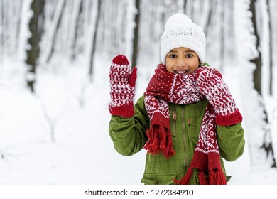 African American Child In Warm Clothing Smiling, Waving With Hand And Looking At Camera In Winter Park