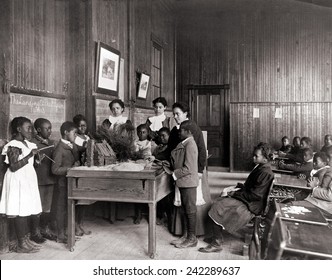 African American children learning about Thanksgiving, with model log cabin on table, Whittier Primary School, Hampton, Virginia. Ca. 1899.
