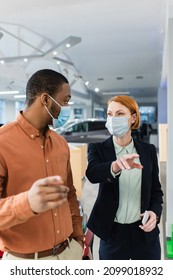 African American Client And Car Dealer In Medical Masks Looking At Each Other In Showroom