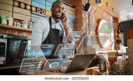 African American Coffee Shop Owner Is Working On Computer And Talking On A Phone In A Cute Cafe. Augmented Reality Icons Popping Out Of Restaurant Manager's Laptop: Small Black Business Concept.
