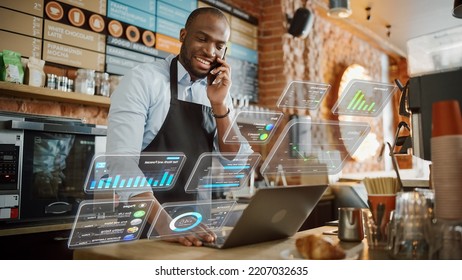African American Coffee Shop Owner Is Working On Computer And Talking On A Phone In A Cozy Cafe. Augmented Reality Icons Popping Out Of Restaurant Manager's Laptop: Small Black Business Concept.