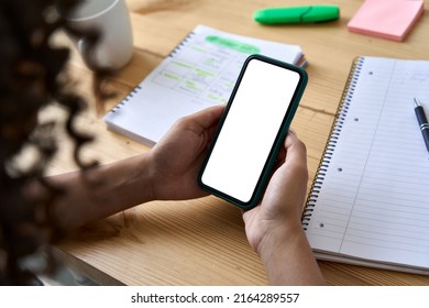 African American college girl student holding phone distance learning class using mobile tech, watching online video lesson in app studying at home school, over shoulder mock up screen view.