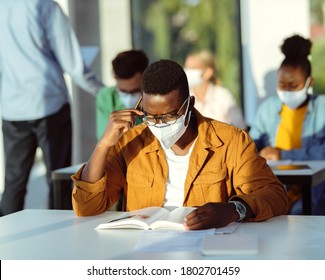 African American College Student With Face Mask Reading A Book While Learning In The Classroom. 