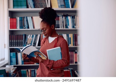 African American college student reading book while studying in library. Copy space. - Powered by Shutterstock