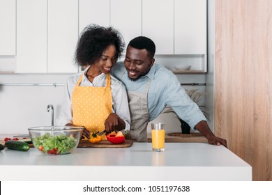 African American Couple In Aprons Standing At Table And Cooking