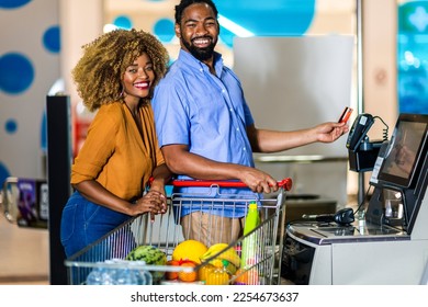 African American Couple with bank card buying food at grocery store or supermarket self-checkout - Powered by Shutterstock