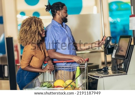 African American Couple with bank card buying food at grocery store or supermarket self-checkout