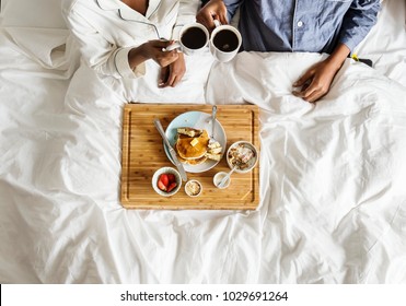 African American couple in bed having a breakfast in bed - Powered by Shutterstock