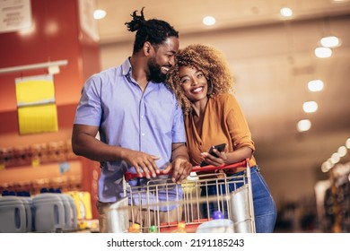 African American couple choosing products using phone during grocery shopping in modern supermarket - Powered by Shutterstock