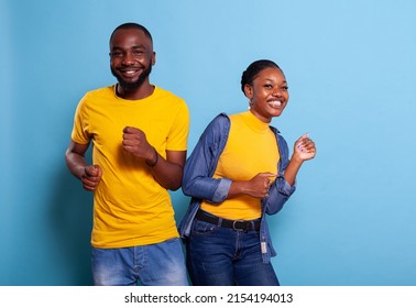 African American Couple Doing Dance Moves Together In Studio, Feeling Cheerful And Carefree. Happy People Dancing On Rhythm And Smiling In Front Of Camera, Having Fun In Relationship.