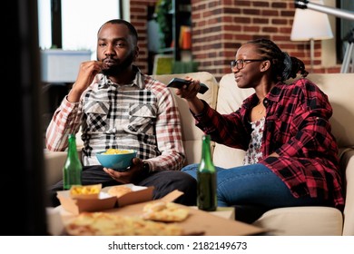 African American Couple Eating Takeaway Food And Switching Channels On Television, Searching For Movie. Enjoying Takeout Delivery Meal And Beer In Front Of Tv Film, Leisure Activity.