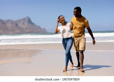 African american couple embracing walking on a beach by the sea. healthy lifestyle, leisure in nature.