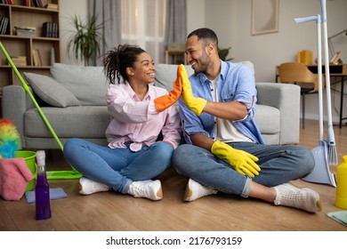 African American Couple Giving High Five Cleaning House Doing Housework Together Sitting On Floor In Modern Living Room At Home. Family Lifestyle, House Chores Concept - Shutterstock ID 2176793159