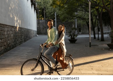 African american couple, having fun in the city park riding a bicycle - Powered by Shutterstock