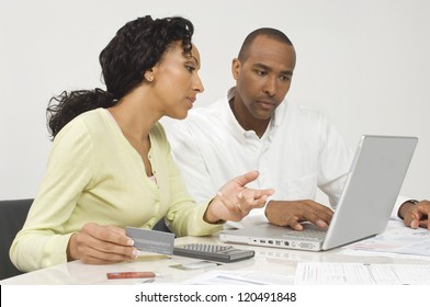 An African American couple paying bills online at home