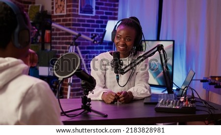 African american couple recording vlog using digital camera while recording podcast using professional microphone and audio equipment. Content creator interviewing famous vlogger in home studio.