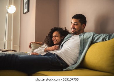 African american couple relaxing at home and watching tv.
