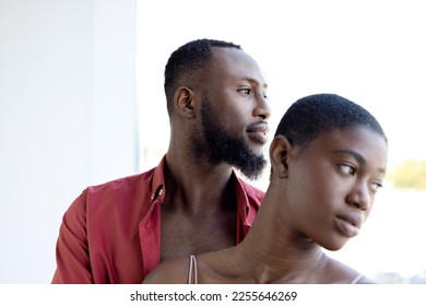 African American couple with short hair cuddling near window on sunny day. Woman and man looking away, breaking up romance affair concept. Horizontal copy space - Shutterstock ID 2255646269