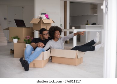 African American Couple Sitting In A Box Playing With Packing Material, Having Fun After Moving In New Home