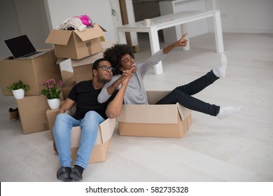 African American Couple Sitting In A Box Playing With Packing Material, Having Fun After Moving In New Home