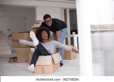 African American Couple Sitting In A Box Playing With Packing Material, Having Fun After Moving In New Home