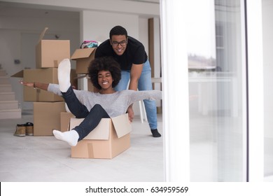 African American Couple Sitting In A Box Playing With Packing Material, Having Fun After Moving In New Home