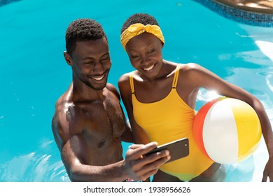 African American Couple In Swimming Pool Taking Selfie And Smiling. Staying At Home In Isolation During Quarantine Lockdown.