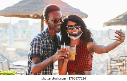 African American Couple Taking Selfie In Beach Party - Young Friends With Face Mask Drinking Cocktail In Holiday - Coronavirus Summer 2020