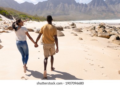 African american couple walking holding hands on a beach by the sea. healthy lifestyle, leisure in nature.